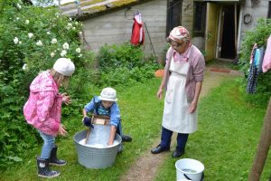 Lasten perinnepäivä koostuu työkokeiluista ja leikeistä. Kuvassa Eila Lempinen näyttää pyykinpesua pyykkilaudalla.
