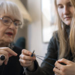 Ikäihminen opettaa nuorta neulomaan