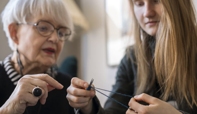 Ikäihminen opettaa nuorta neulomaan