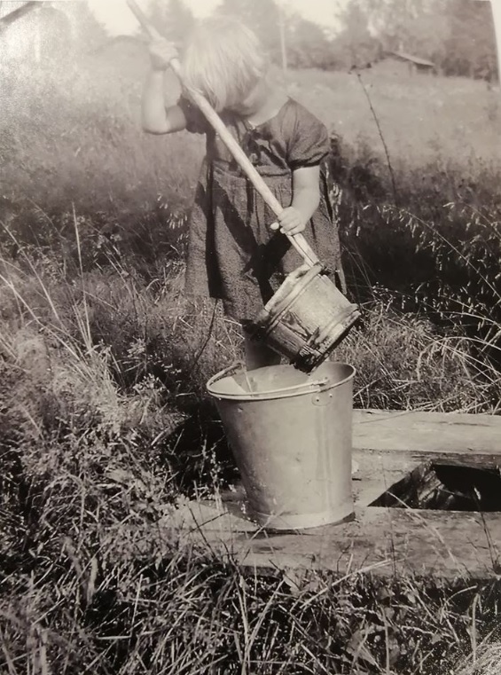 Vanha valokuva, jossa on tyttö hakemassa vettä.
