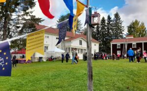 Etualalla nurmikkoa ja viirejä. Taustalla vanhoja rakennuksia ja ihmisiä.