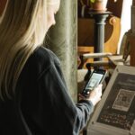 nainen skannaan puhelimella qr-koodia museossa