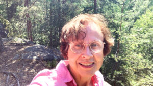 Virpi Hämeen-Anttila kirkkaana kesäpäivänä, taustalla kalliota ja mäntymetsää.