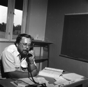 Mustavalkoinen valokuva Markku Tannerista puhumassa lankapuhelimeen.