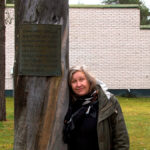 Eeva Snellman nojaa kelopuuhun, johon on kiinnitetty kyltti. Teos on pystytetty Sodankylän vapauttamisen 20.10.1944 vuosipäivänä 1974.