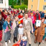 Riemuitsevia monenikäisiä ihmisiä Kumpulassa, Helsingissä, taustalla kerrostaloja.