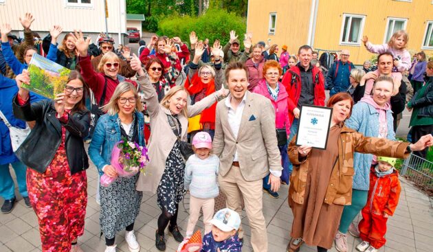 Riemuitsevia monenikäisiä ihmisiä Kumpulassa, Helsingissä, taustalla kerrostaloja.