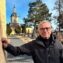 Erkki Taskila nojaa vanhaan rakennukseen. Taustalla on kirkon torni.